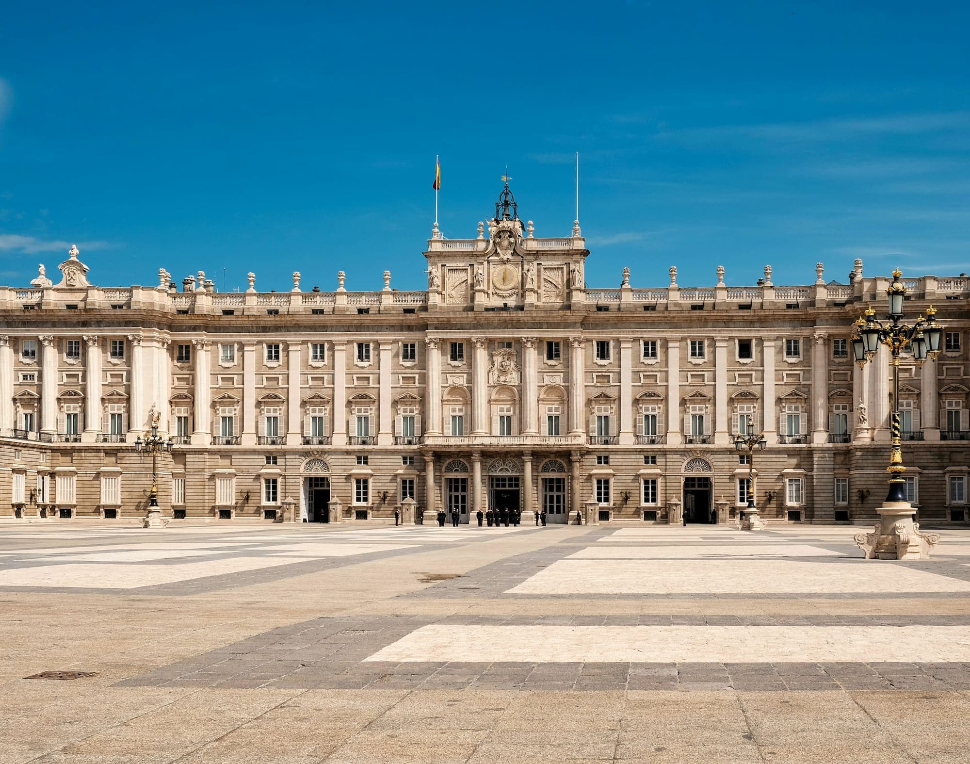 Royal Palace of Madrid seen from the Plaza de la Armería under a blue sky